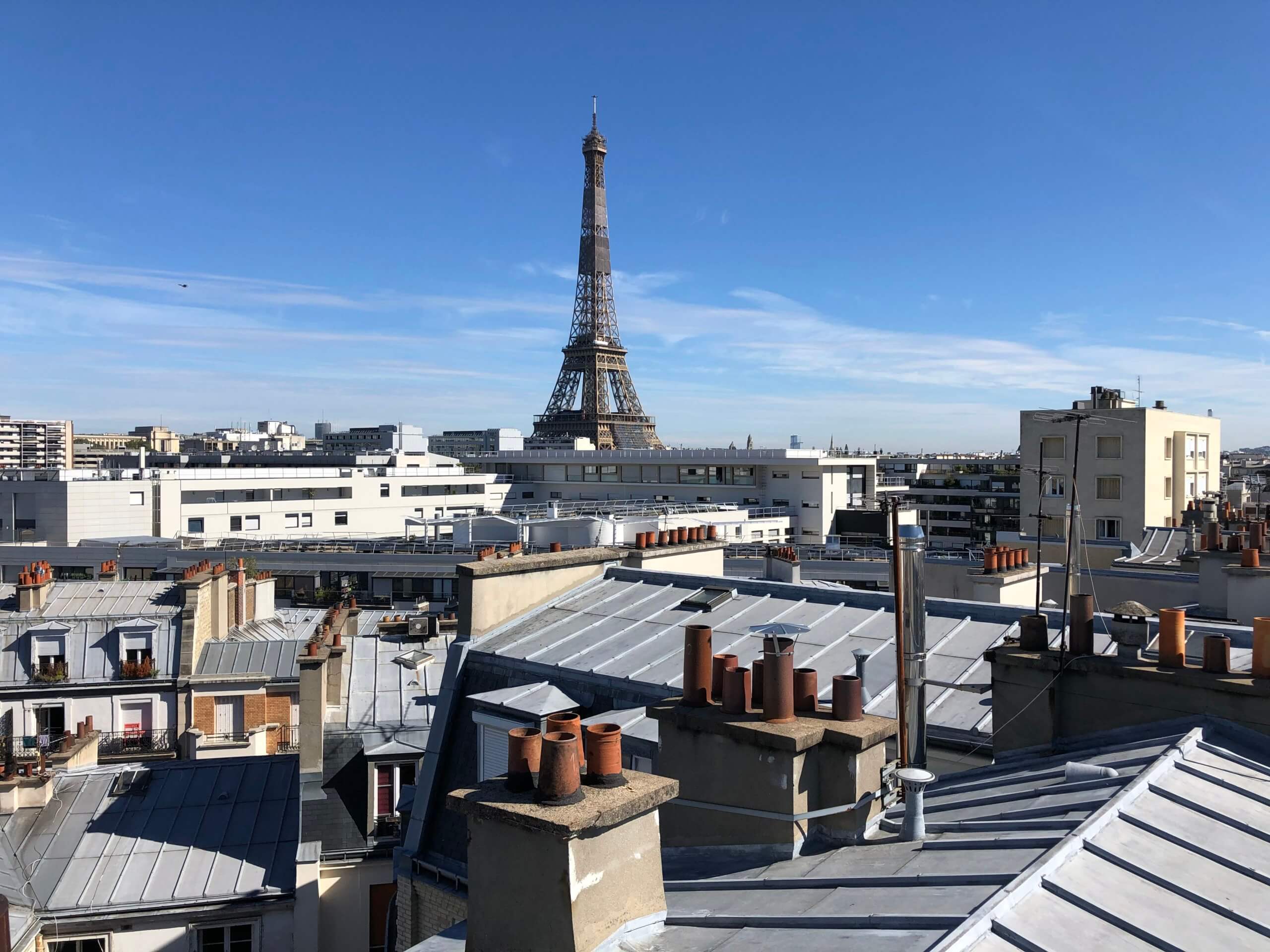 Toits de paris avec la tour eiffel en fond qui illustre la position centrale de l'entreprise au sein de la capitale